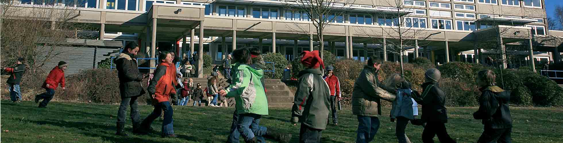 Spielende Kinder vor eine Schule