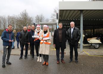 Menschen stehen auf einem Parkplatz. Zwei Frauen tragen Nikolaus-Mützen. Die Menschen arbeiten für die Stadt oder die Firma Neff