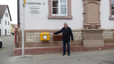 Stolz präsentiert Ortsvorsteher Martin Kern den neuen Briefkasten an der Ortsverwaltung Diedelsheim. Foto: Nina Kraus, Stadt Bre