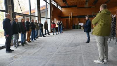 Menschen stehen in einer Sporthalle. In der Halle finden Bauarbeiten statt.