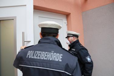 Gemeindevollzugsbedienstete vor einer Haustür.
