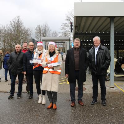 Menschen stehen auf einem Parkplatz. Zwei Frauen tragen Nikolaus-Mützen. Die Menschen arbeiten für die Stadt oder die Firma Neff