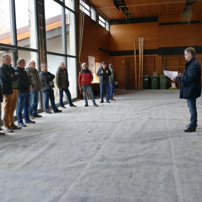 Menschen stehen in einer Sporthalle. In der Halle finden Bauarbeiten statt.
