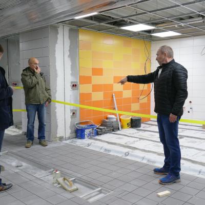 Menschen stehen in einer Sporthalle. In der Halle finden Bauarbeiten statt.